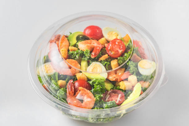 istock Plastic package with healthy shrimp caesar salad with avocado , kale, tomatoes and eggs to take away. close up 1272459184
