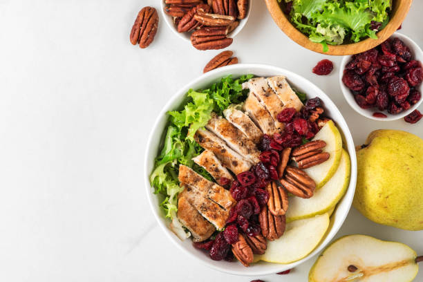 ketogenic paleo diet lunch bowl salad. Grilled chicken breast, pear, pecan nuts, dried berries and salad leaves. top view ketogenic paleo diet lunch bowl salad. Grilled chicken breast, pear, pecan nuts, dried berries and salad leaves on white background. top view salad fruit lettuce spring stock pictures, royalty-free photos & images