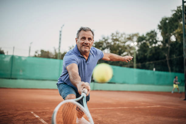 aktiver älterer mann, der tennis spielt - tennis active seniors healthy lifestyle senior men stock-fotos und bilder