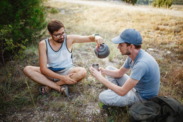 istock Outdoors image of young explorer man drinking hot beverage in mountains, sitting and relaxing after trekking 1272461633