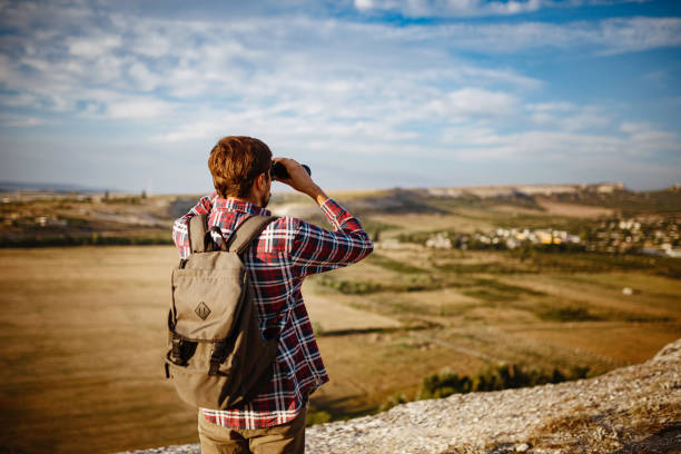 istock Guy looking at binoculars in hill. man in t-shirt with backpack 1272461752