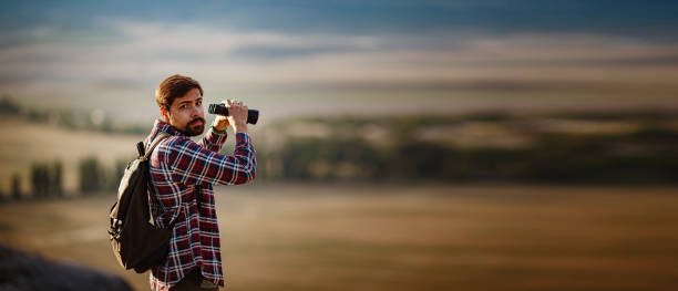 istock Guy looking at binoculars in hill. man in t-shirt with backpack 1272461911