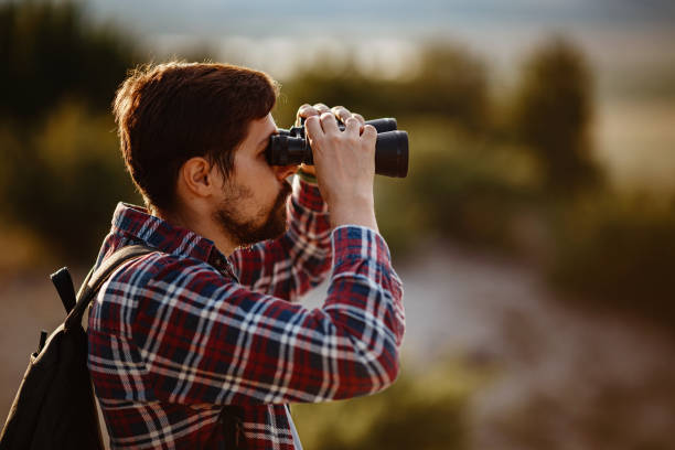 istock Guy looking at binoculars in hill. man in t-shirt with backpack 1272462306