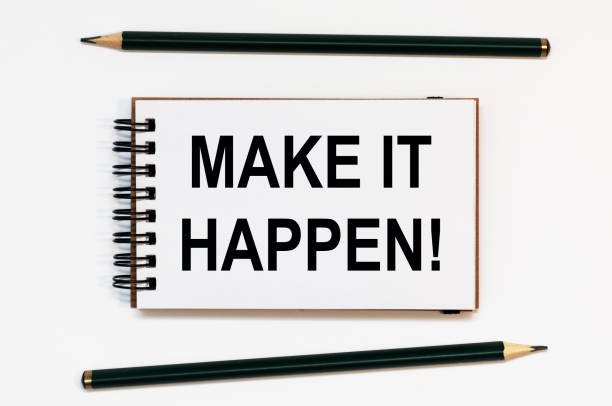 istock WHITE SPIRAL NOTEBOOK, TWO PENCILS WITH TEXT MAKE IT HAPPEN 1272462428