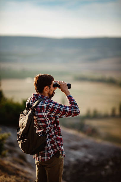 istock Guy looking at binoculars in hill. man in t-shirt with backpack 1272462865