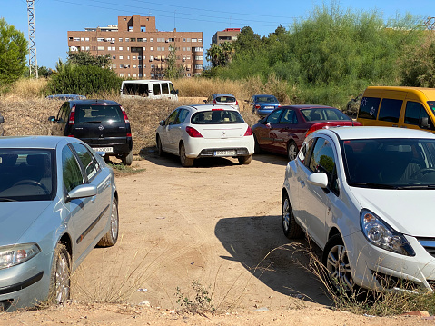 Valencia, Spain - September 11, 2020: many cars parking in empty unused piece of land in the middle of the city. Commuters use every resource they have to park their cars in this city