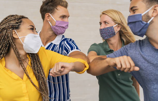 istock Young friends wearing face protective mask doing new social distancing greet with elbows bumps for preventing corona virus spread - Physical distance and friendship safety greetings concept 1272463021