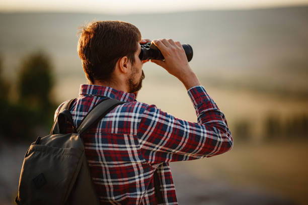 istock Guy looking at binoculars in hill. man in t-shirt with backpack 1272463588