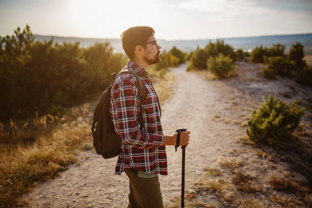 istock man hiking in the mountains using pole and looking away 1272464176