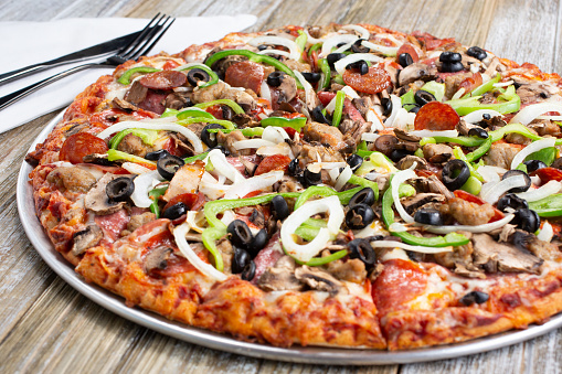 A view of a meat and veggie pizza pie, in a restaurant or kitchen setting.
