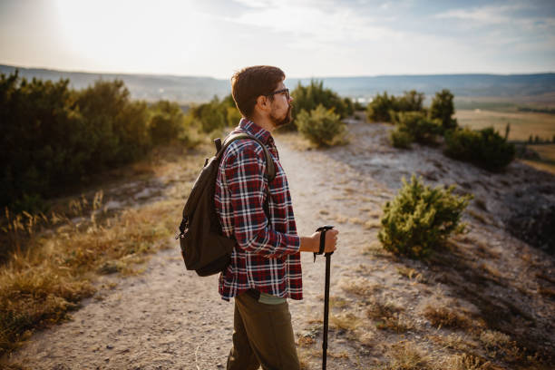 istock man hiking in the mountains using pole and looking away 1272466895