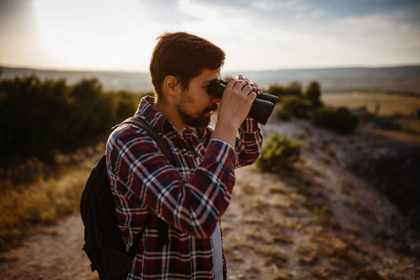 istock Guy looking at binoculars in hill. man in t-shirt with backpack 1272466910