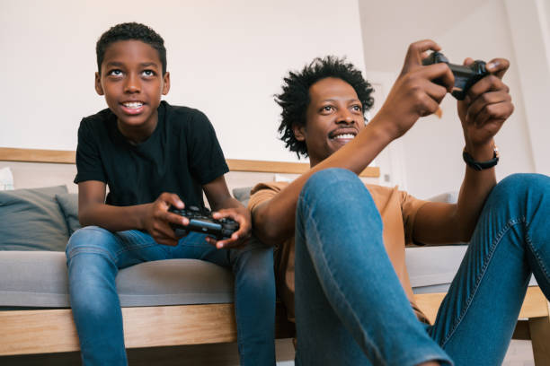 istock Father and son playing video games together at home. 1272467100