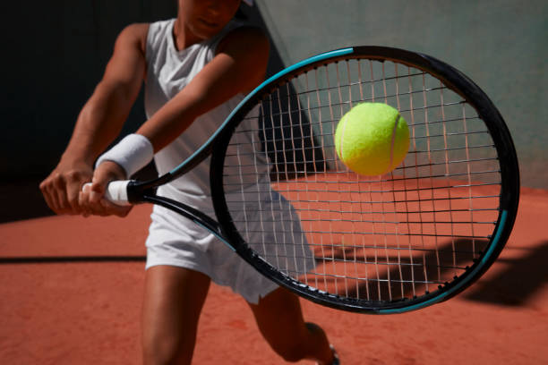 mulher de close-up batendo bola durante partida de tênis em quadra de barro - raquete de ténis - fotografias e filmes do acervo