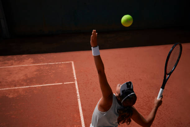 professionelle tennisspielerin, die während des spiels ball serviert - tennis court sport ball stock-fotos und bilder