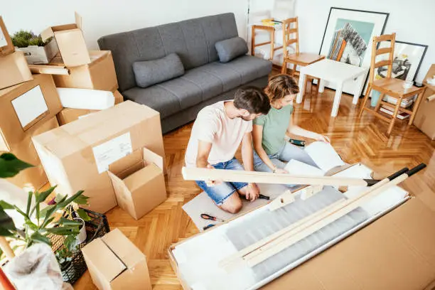 Couple moving in new apartment and assembling furniture