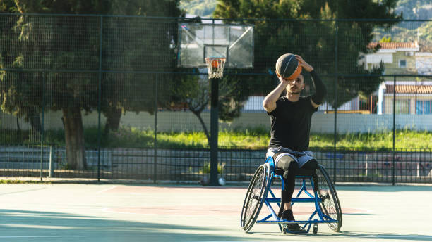 junger stattaussehender mann im rollstuhl spielt basketball - men chair wheelchair sport stock-fotos und bilder