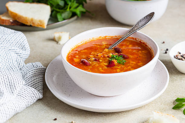 un tazón de sopa casera de frijoles rojos y lentejas, pan y perejil sobre fondo de piedra. sopa picante de verduras. - lentil dinner holiday mediterranean cuisine fotografías e imágenes de stock