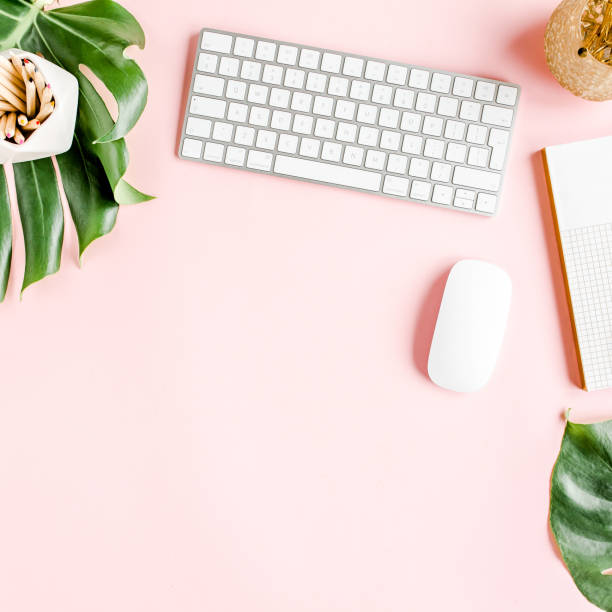 istock Flat lay home office desk. Female workspace with computer, tropical palm leaves Monstera, accessories on pink background. Top view background 1272475922