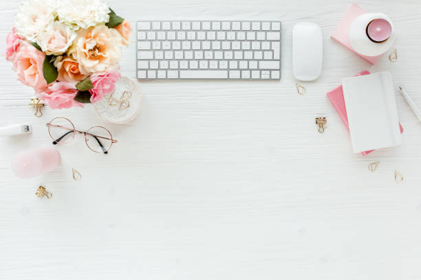 istock Flat lay women's office desk. Female workspace with computer, pink roses flowers, accessories, golden diary, glasses on white background. Top view 1272478555