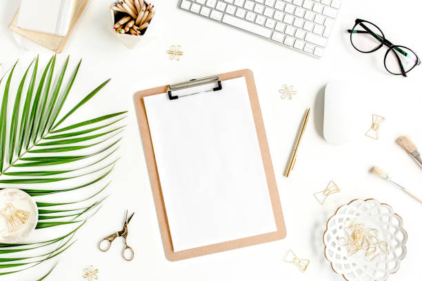 istock Flat lay home office desk. Female workspace with computer, clipboard, tropical palm leaves, accessories on white background. Top view 1272479791