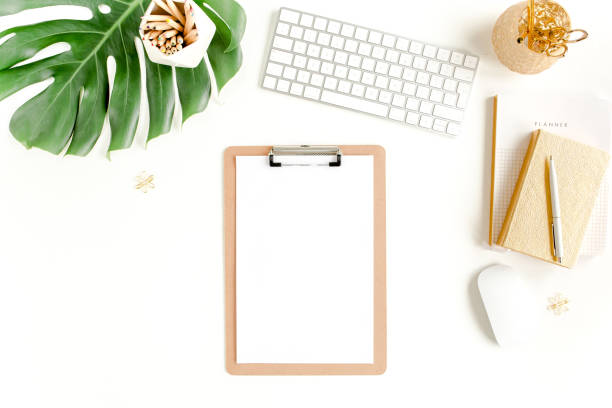 istock Flat lay home office desk. Female workspace with computer, clipboard, tropical palm leaves Monstera, accessories on white background. Top view 1272479995