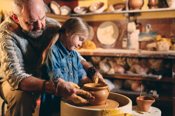 istock Pottery workshop. Grandpa teaches granddaughter pottery. Clay modeling 1272480956