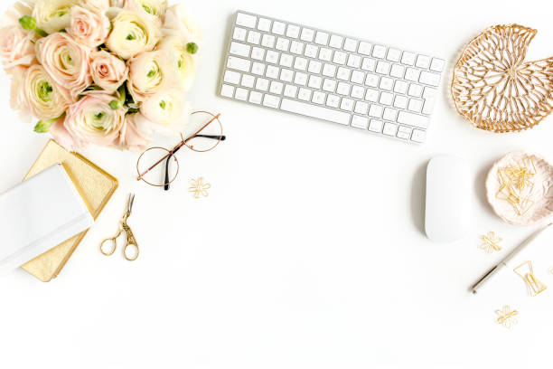 istock Stylized women's home office desk. Workspace with computer, bouquet ranunculus and roses, clipboard on white background. Flat lay. Top view 1272481063