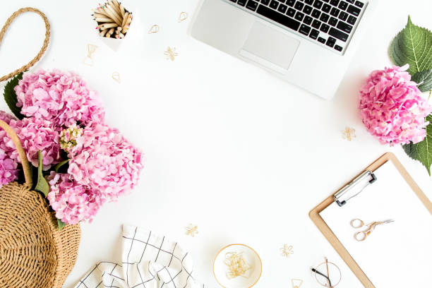 istock Workspace with clipboard, laptop, bouquet hydrangea, accessories on white background. Stylized women's desk. Flat lay. Top view 1272482286