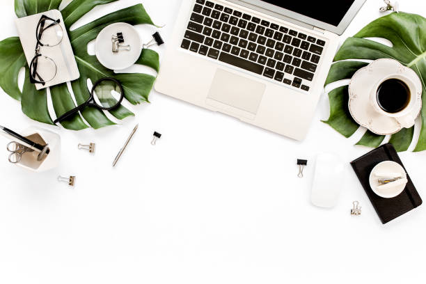 istock Home office workspace mockup with laptop, tropical leaves Monstera, clipboard, notebook and accessories on white background. Flat lay, top view 1272482352
