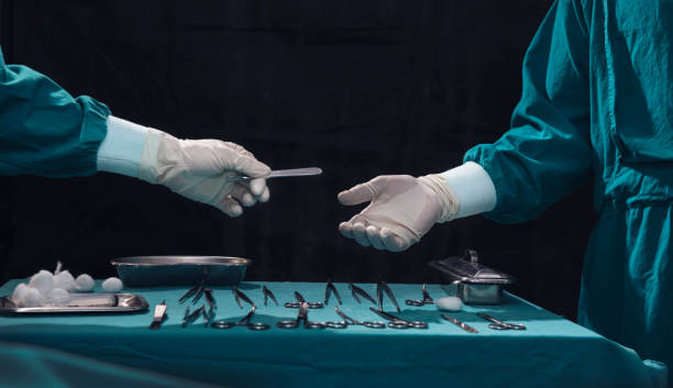 Surgery team operating in a surgical room.Assistant passing surgical scalpel to the doctor. Surgery team operating in a surgical room.Assistant passing surgical scalpel to the doctor. Hand of doctor in white glove. Two surgeons working and passing surgical equipment in the operating room scalpel stock pictures, royalty-free photos & images