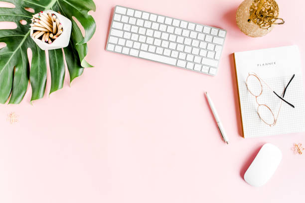 istock Flat lay home office desk. Female workspace with computer, tropical palm leaves Monstera, accessories on pink background. Top view background 1272483371