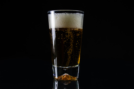 Glass of cold beer on black background