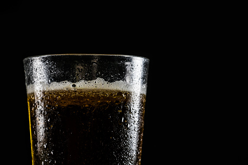 Glass of cold beer on black background