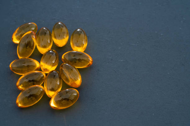 cápsulas ômega 3 em fundo preto - capsule pill lecithin fish oil - fotografias e filmes do acervo