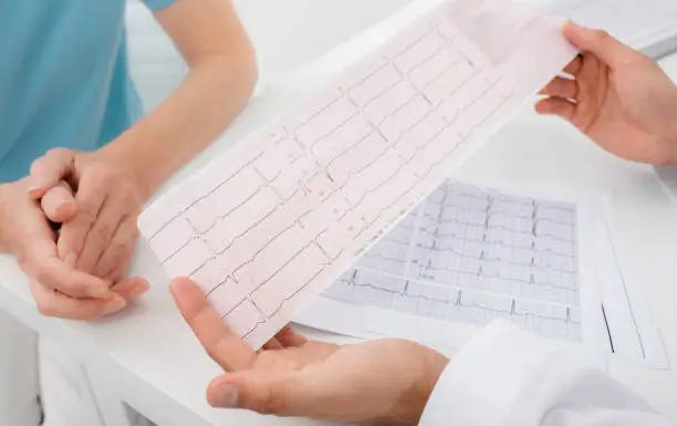 Photo of Doctor analyzes the electrocardiogram results, close-up. Diagnosis of arrhythmia, heart rate and heart disease