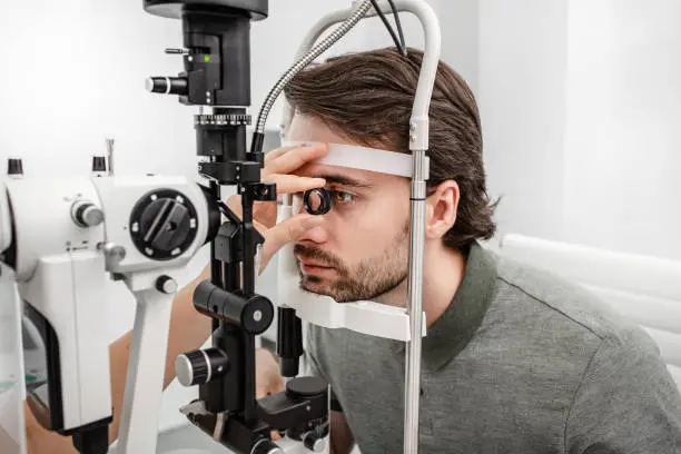 Adult man eyesight test with binocular slit-lamp. Checking retina of a male eye close-up. Ophthalmology Clinic