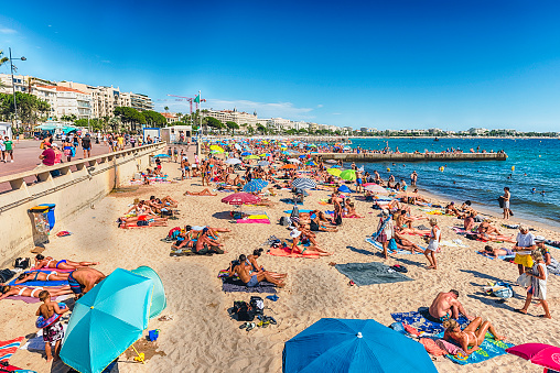 CANNES, FRANCE - AUGUST 15: People enjoying a sunny day on the beach in Cannes, Cote d'Azur, France, as seen on August 15, 2019