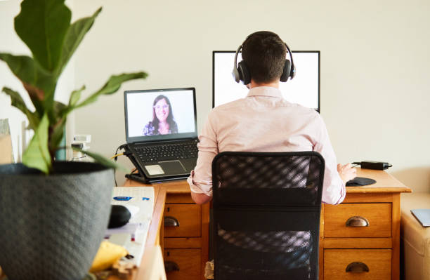 istock Man video calling with a colleague while working remotely from home 1272490295