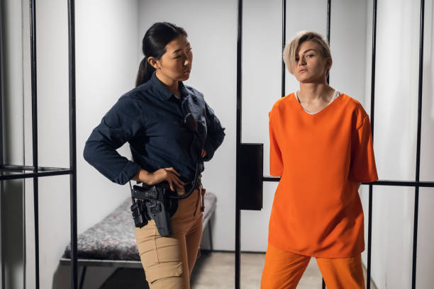 Asian warden and a female prisoner in a high-security prison stand in front of an open cell stock photo
