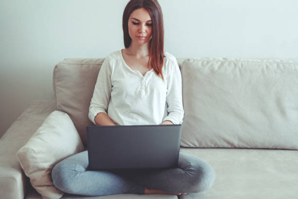 istock Woman sitting on a sofa at home and using laptop. 1272492759
