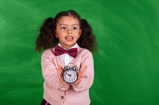 School African-American Child with Alarm Clock Show Time Back to School in front blackboard