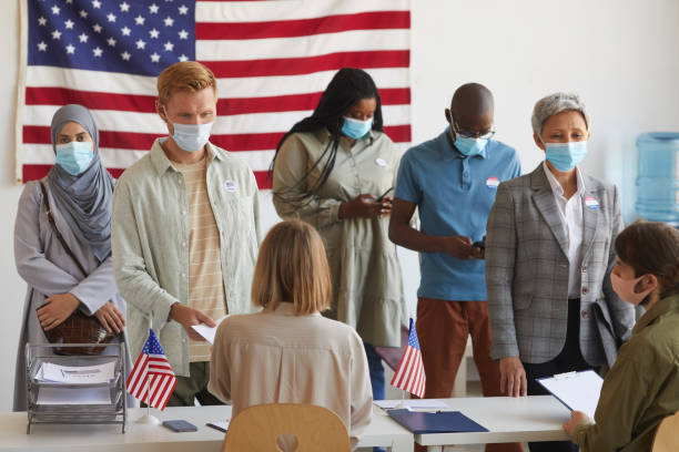 Post-Pandemic Voting Multi-ethnic group of people standing in row and wearing masks at polling station on election day ballot measure stock pictures, royalty-free photos & images