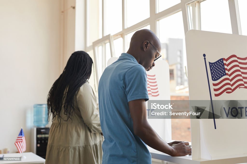 African-American People in Voting Booth Back view portrait of young African-American people standing in voting booth and thinking, copy space Voting Stock Photo