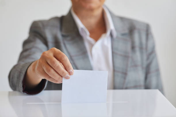 istock Woman Putting Envelope in Ballot Box Close Up 1272497429