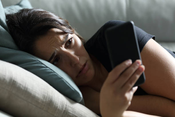 istock Sad woman checking phone in the dark at home 1272497619