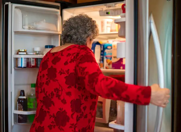Photo of Senior woman take food from a refrigerator.