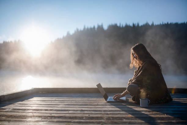 donna che si rilassa nella natura e usa la tecnologia. - light relaxation blue lake foto e immagini stock