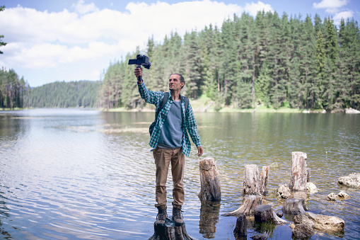 Male backpacker travelling in nature and vlogging.