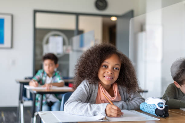 istock Smiling elementary girl working at desk 1272506423